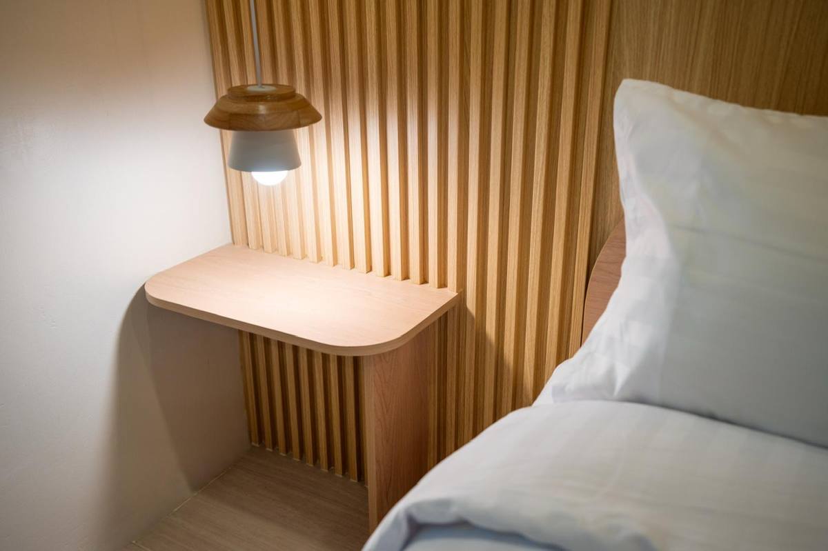 Kinza guest room — white linen bed against a warm wood-slat wall